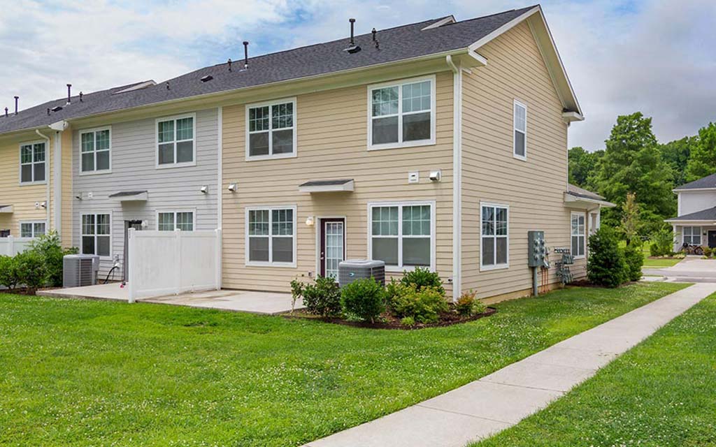 a yellow house with a sidewalk in front of it