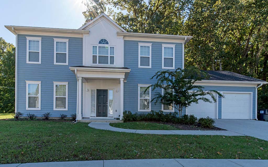 a blue house with a sidewalk in front of it