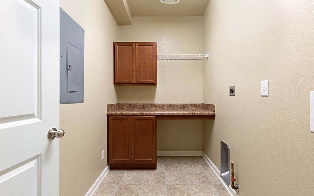 an empty laundry room with a counter and cabinets