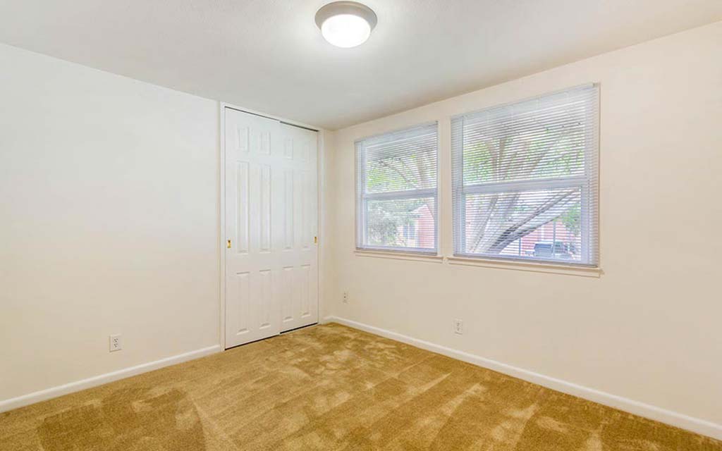 an empty bedroom with a door and a window