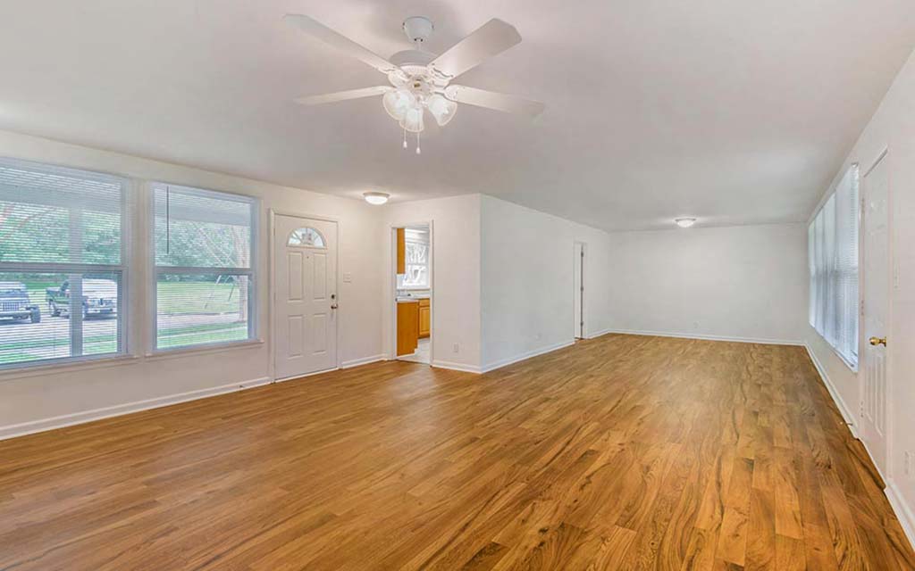 an empty living room with wood floors and a ceiling fan