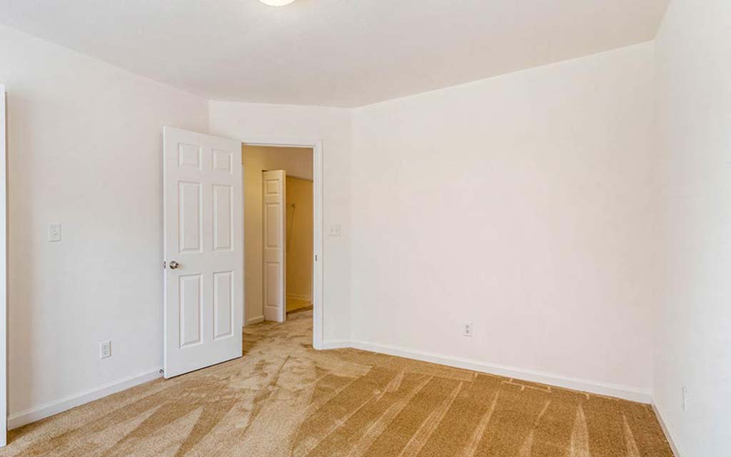 an empty living room with a door to a closet