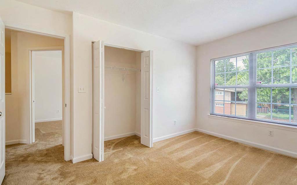 an empty bedroom with a large window and a closet
