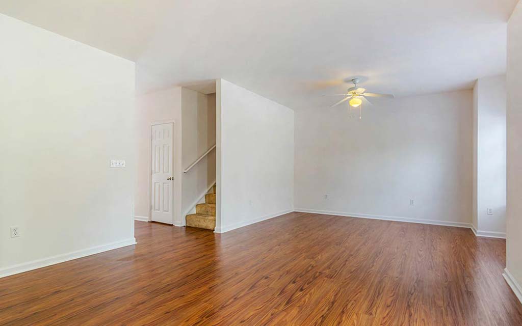 an empty living room with wood floors and a ceiling fan