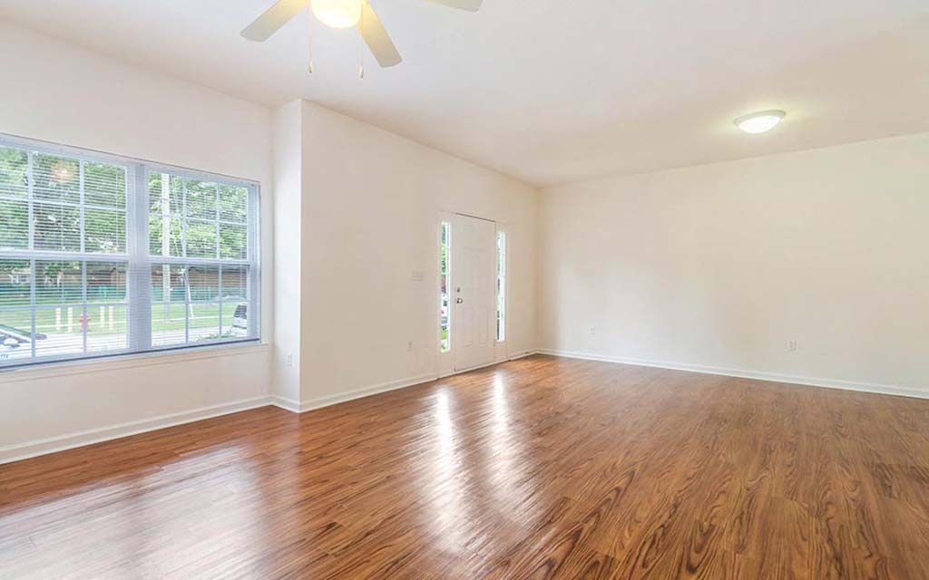 an empty living room with wood floors and a window