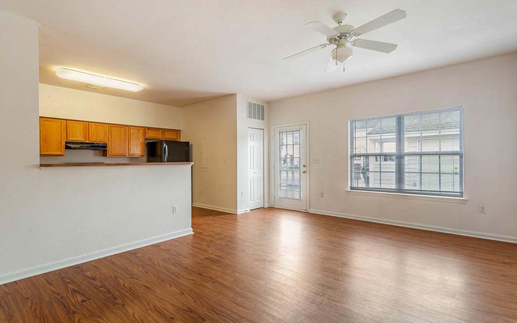 an empty living room with a ceiling fan and a window