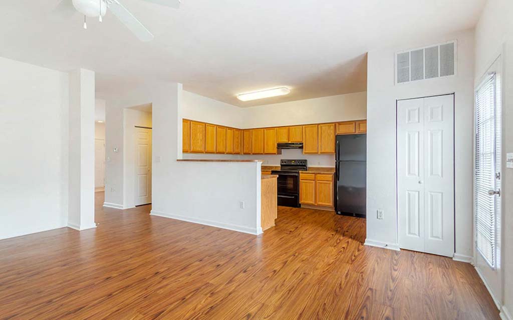 an empty living room and kitchen with wood floors