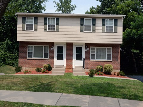 A two-story house with a red brick base and a white top.