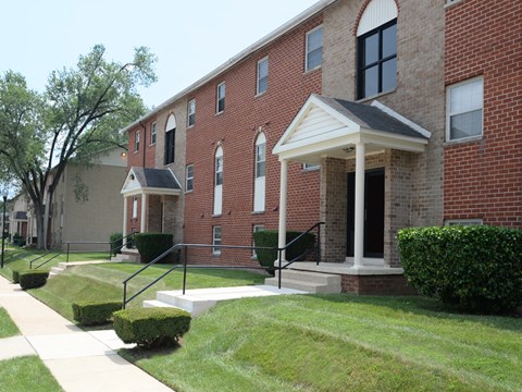 A red brick building with a white porch and a black railing.