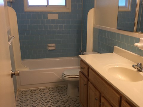 A bathroom with a toilet, sink, and a window.