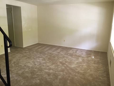 A room with a carpeted floor and a door on the left side.