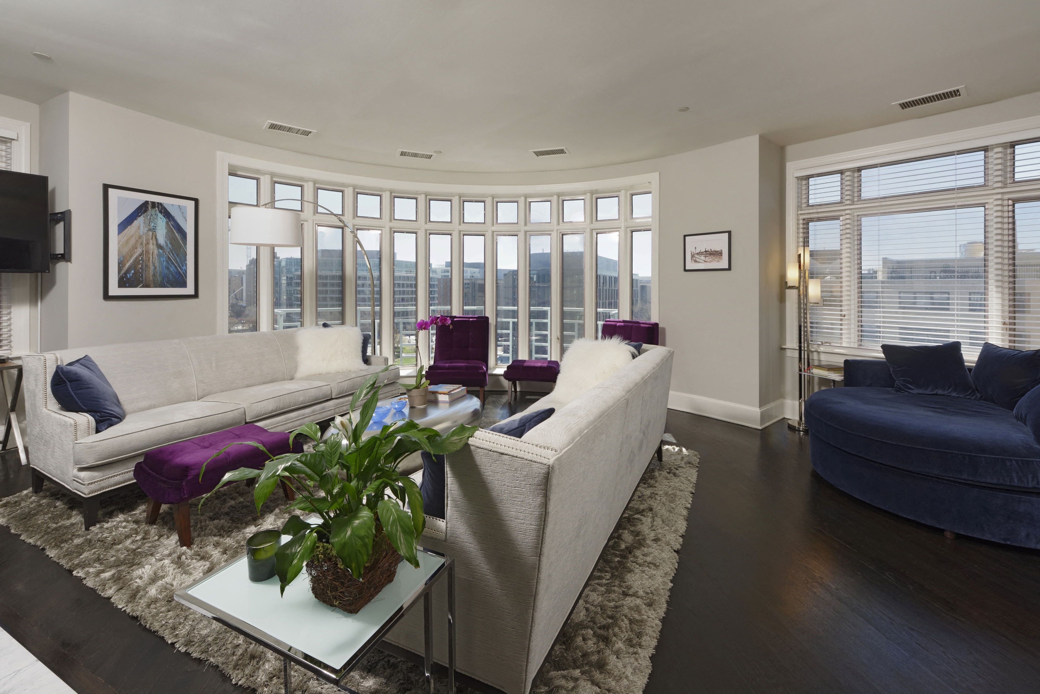 a living room with white couches and purple chairs and a table