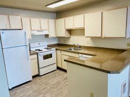 an empty kitchen with white appliances and white cabinets