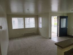 an empty living room with windows and a door