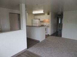 an empty living room with a kitchen in it