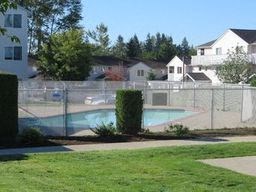 a swimming pool in a yard behind a chain link fence