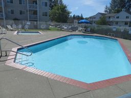 an empty swimming pool with chairs around it and a building in the background