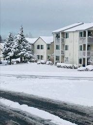 a snow covered street in front of an apartment building