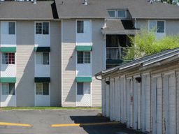 an apartment building with green and white siding and a garage door
