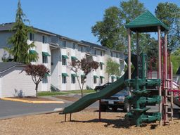 a playground with a green slide in front of a building