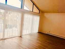 an empty living room with wood floors and a large window