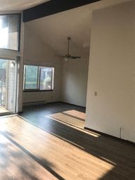 an empty living room with wood floors and a ceiling fan