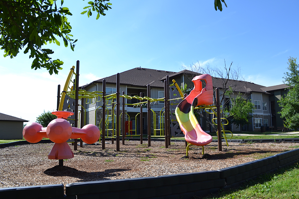 a playground with a slide and other toys in front of a house