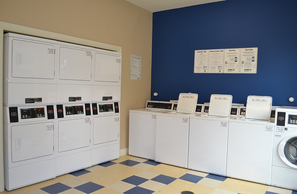 a laundry room with washers and dryers and a blue wall and a row