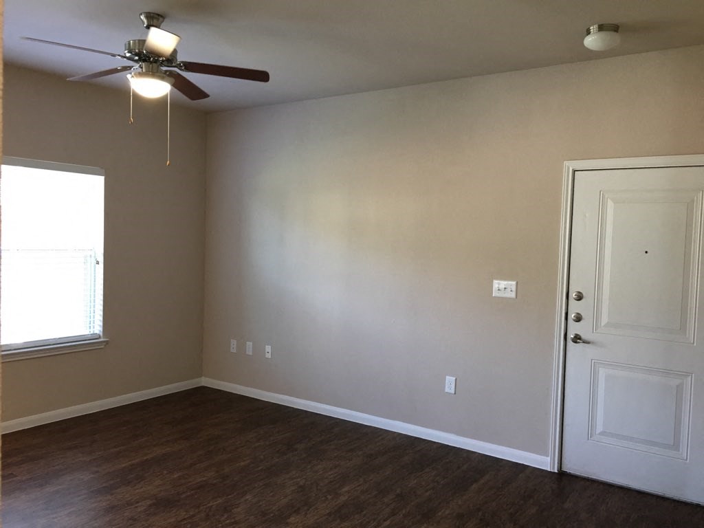 an empty living room with a ceiling fan and a window