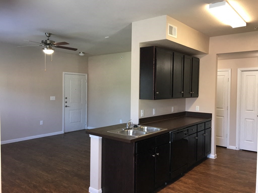 an empty kitchen with a sink and a ceiling fan