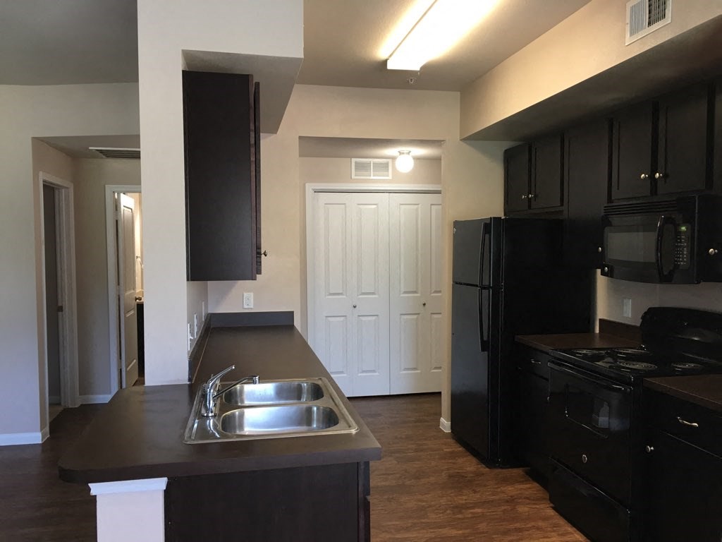 a kitchen with black cabinets and a stainless steel sink