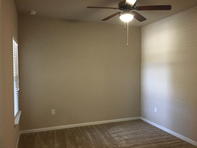 a empty room with a ceiling fan and a window
