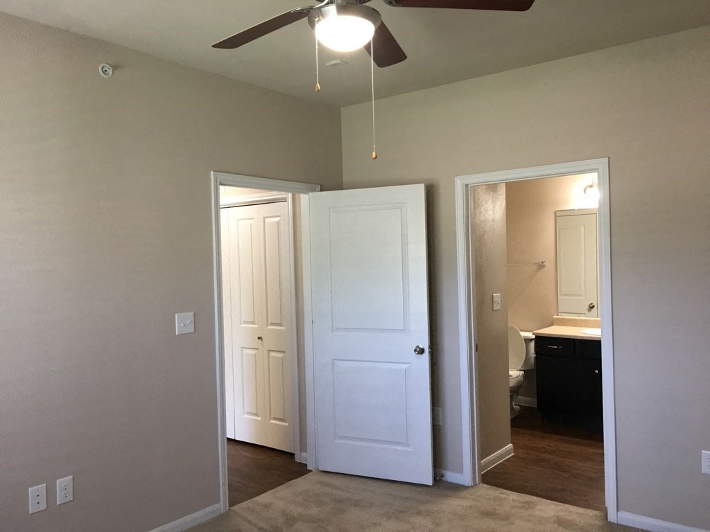 an empty living room with a ceiling fan and two doors