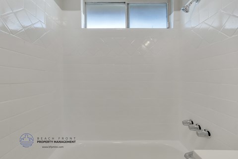 a white bathroom with a tub and a window