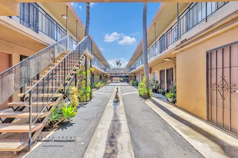 a courtyard between two apartment buildings with stairs and plants