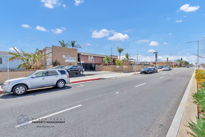 a city street with cars parked on the side of the road and buildings in the background