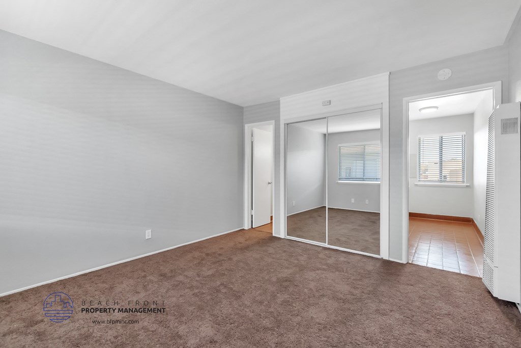 a bedroom with a carpeted floor and a mirrored closet