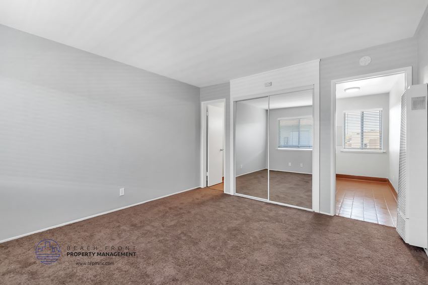 a bedroom with a carpeted floor and a large mirror