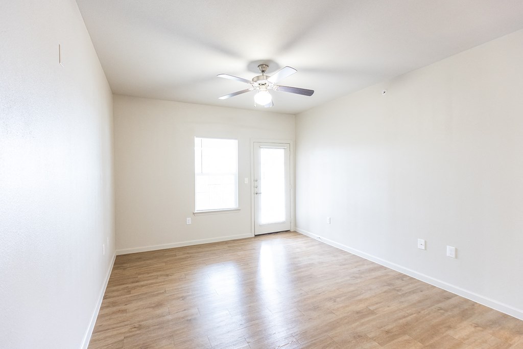 an empty living room with white walls and a ceiling fan