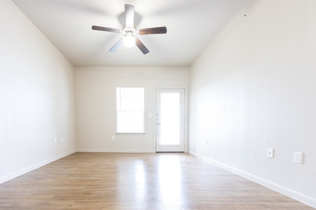an empty living room with white walls and a ceiling fan