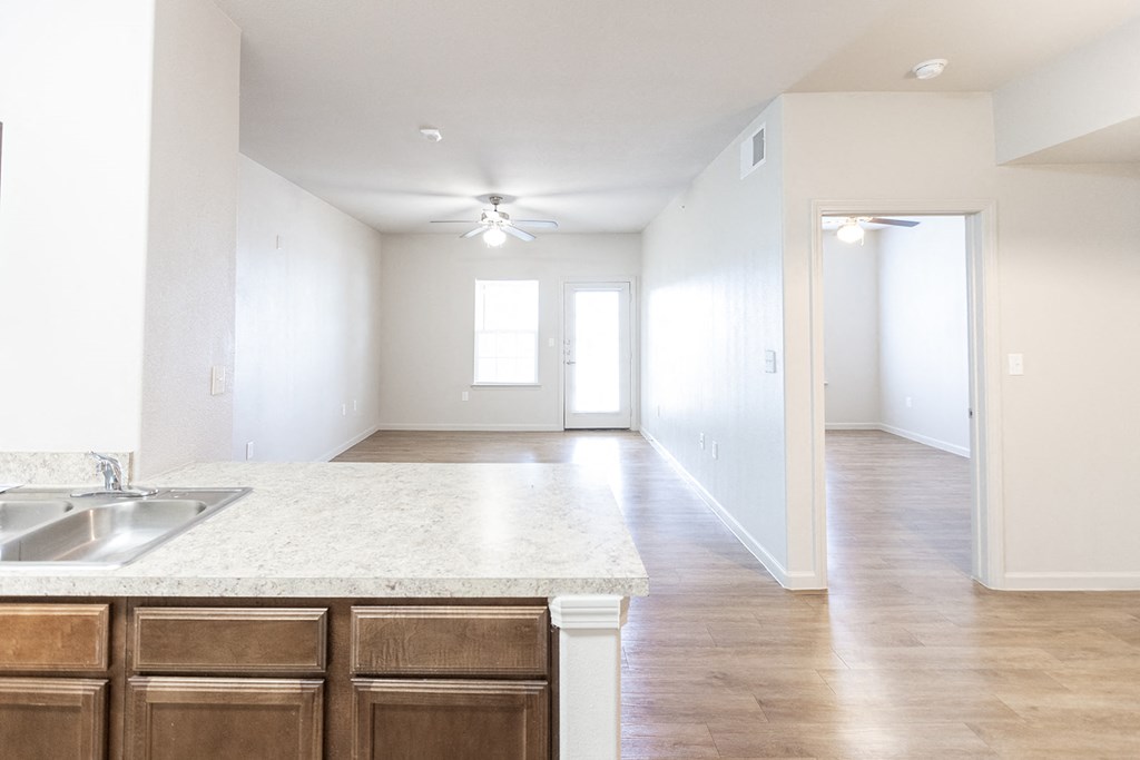 an empty kitchen and living room with white walls and wood flooring