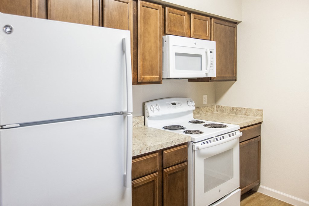 a kitchen with white appliances and wooden cabinets and a refrigerator