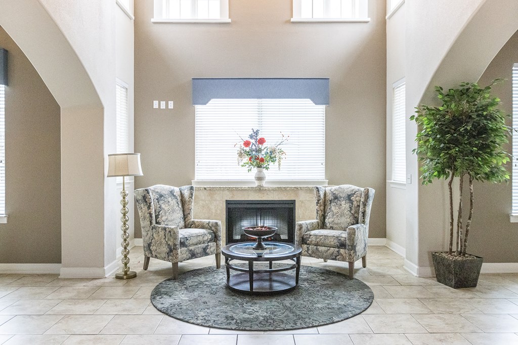 a living room with a fireplace and two chairs and a table