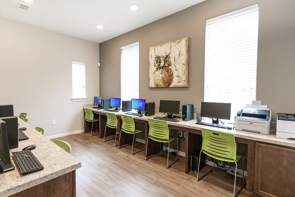 a computer room with green chairs and computers on a table