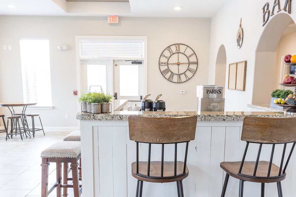 a kitchen with bar stools and a counter with a clock on the wall