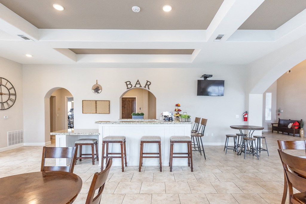 a bar with bar stools and a counter in a living room with a kitchen