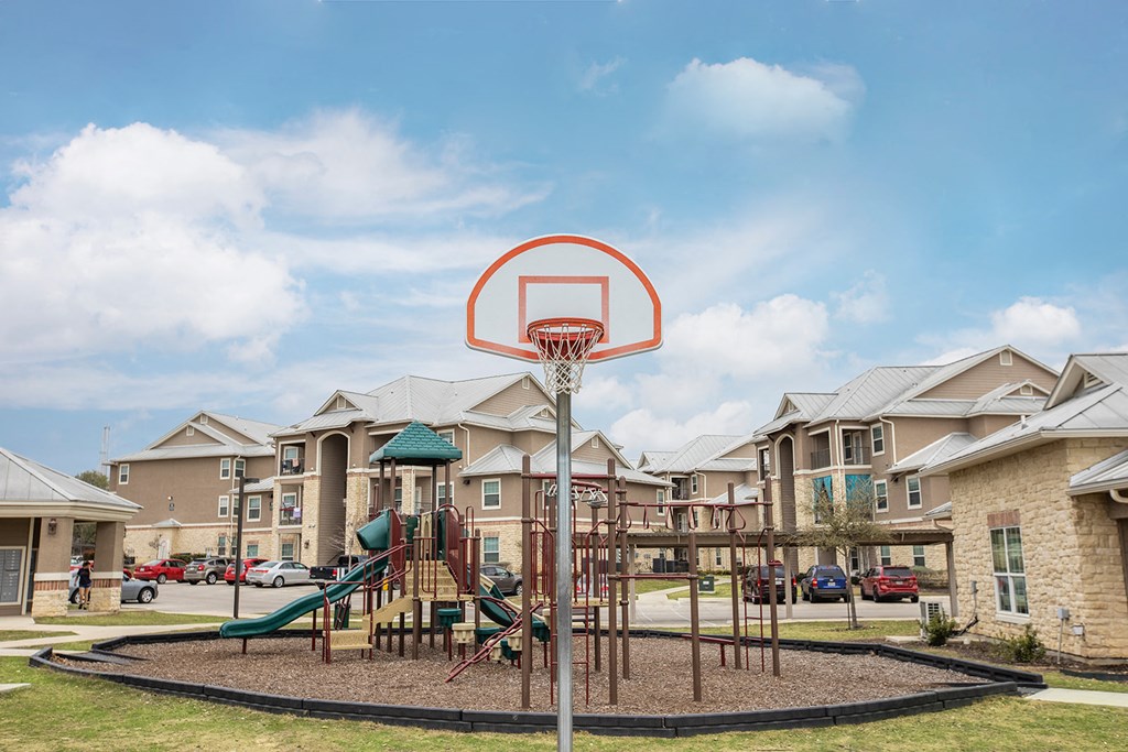 a playground with a basketball hoop in front of apartments