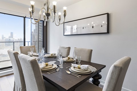 A dining room with a table set for six with a chandelier hanging above.