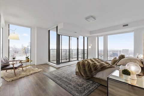 A modern bedroom with a large bed and a view of the city.