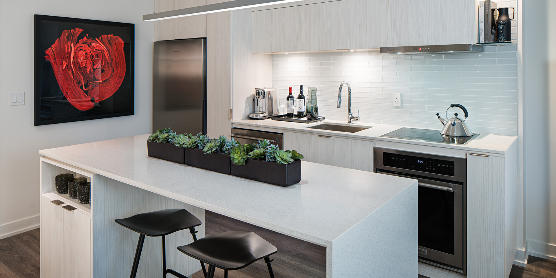 A kitchen with a white counter top and black stools.